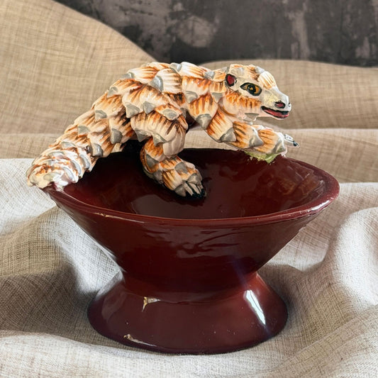 rooibos red ceramic mini raised bowl with a hand sculpted pangolin resting over the rim, head lifted
