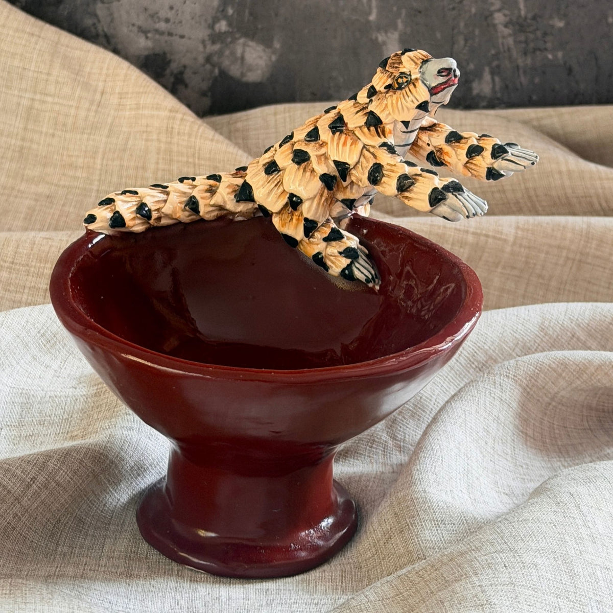 rooibos red ceramic mini raised bowl with a hand sculpted pangolin climbing across the rim, scales tipped in grey